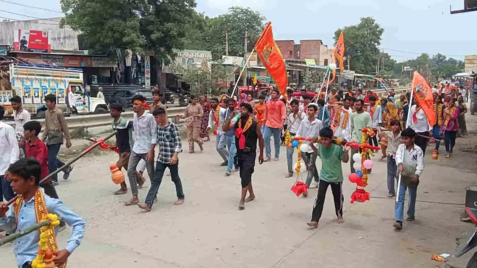 निकुंभ की सड़क पर केसरिया झंडे के साथ कावड़ यात्रा निकालते हुए शिव भक्त। निकुंभ की सड़क पर केसरिया झंडे के साथ कावड़ यात्रा निकालते हुए शिव भक्त।