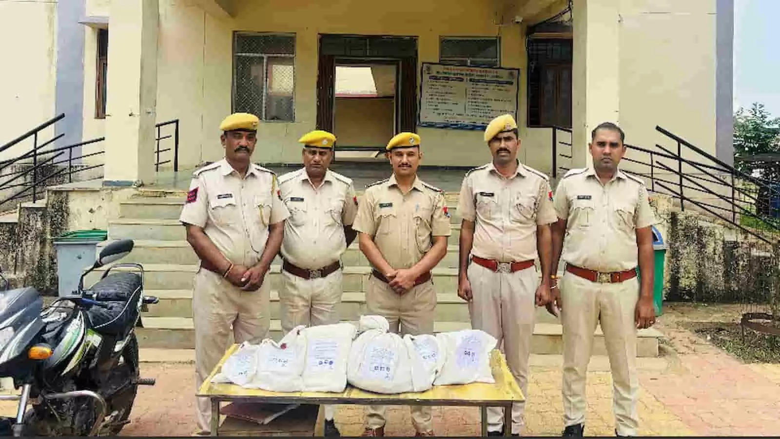 जब्त सफेद बोरियों के साथ चार पुलिसकर्मी डग पुलिस थाने के बाहर खड़े हैं। जब्त सफेद बोरियों के साथ चार पुलिसकर्मी डग पुलिस थाने के बाहर खड़े हैं।