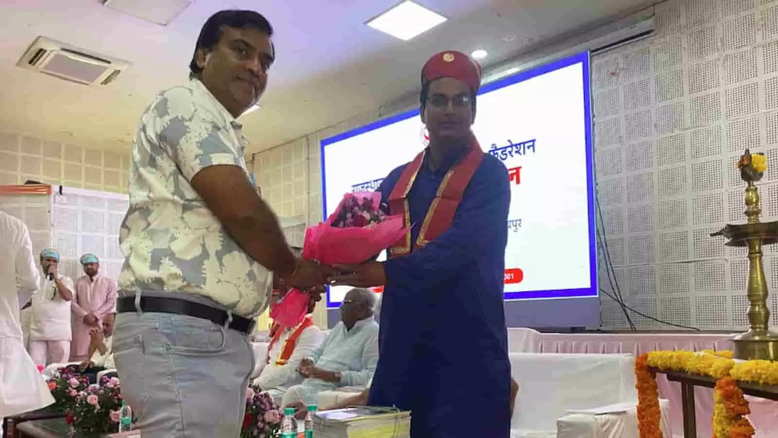 तस्वीर में उदयपुर में आयोजित बैठक के दौरान एक व्यक्ति को गुलदस्ता भेंट करते हुए दिखाया गया है। तस्वीर में उदयपुर में आयोजित बैठक के दौरान एक व्यक्ति को गुलदस्ता भेंट करते हुए दिखाया गया है।
