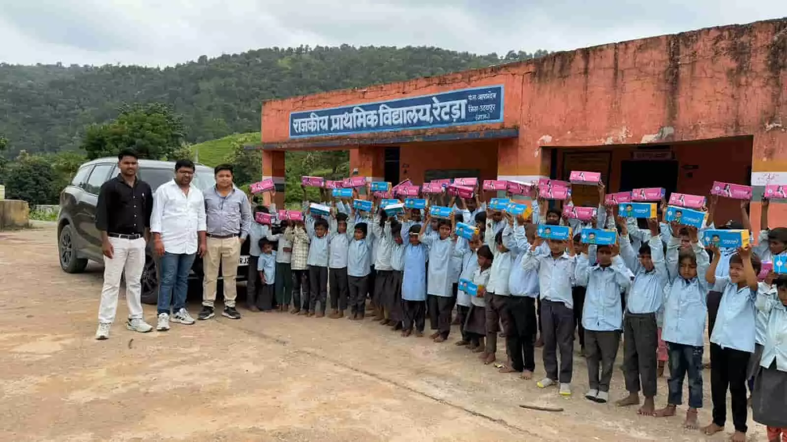 राजकीय प्राथमिक विद्यालय रेटड़ा के बाहर हाथ में जूते के डिब्बे उठाए खड़े बच्चे और अतिथि। राजकीय प्राथमिक विद्यालय रेटड़ा के बाहर हाथ में जूते के डिब्बे उठाए खड़े बच्चे और अतिथि।