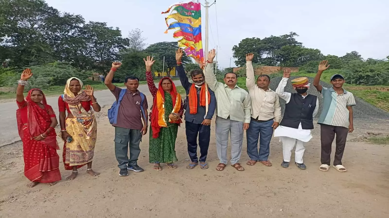कनबई गांव की सड़क पर धार्मिक ध्वज के साथ हाथ उठाकर खड़े रामदेवरा यात्री और उनका स्वागत करते स्थानीय लोग। कनबई गांव की सड़क पर धार्मिक ध्वज के साथ हाथ उठाकर खड़े रामदेवरा यात्री और उनका स्वागत करते स्थानीय लोग।