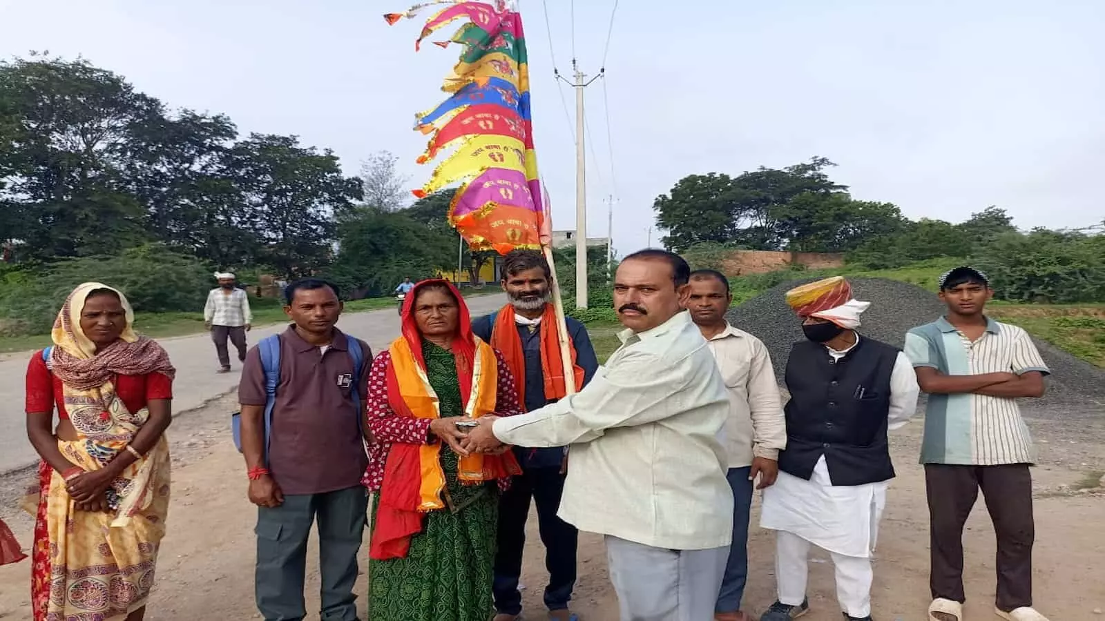 सड़क पर ध्वज थामे पदयात्री महिला को श्रीफल और ऊपरना भेंट कर स्वागत करते लोग। सड़क पर ध्वज थामे पदयात्री महिला को श्रीफल और ऊपरना भेंट कर स्वागत करते लोग।