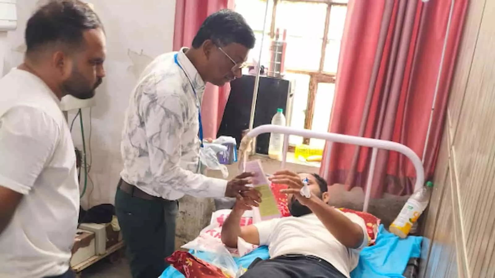 अस्पताल के वार्ड में बिस्तर पर लेटे मरीज को लिटरेचर देते लोग। अस्पताल के वार्ड में बिस्तर पर लेटे मरीज को लिटरेचर देते लोग।