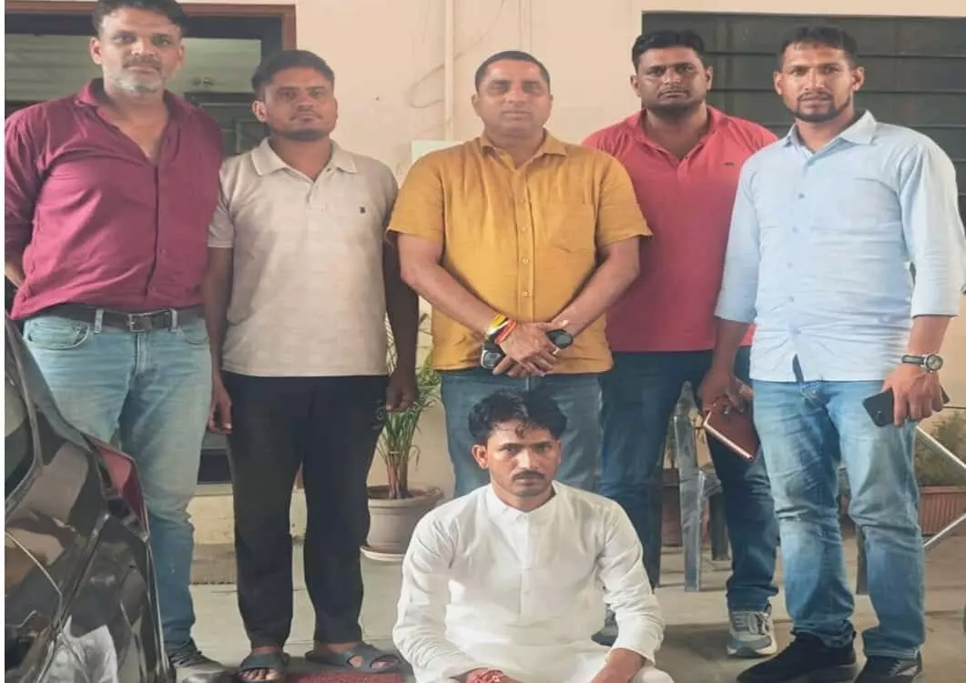 तस्वीर में बैठे हुए अपराधी संदीप राज शर्मा और उनके साथ खड़े पुलिसकर्मी जयपुर में नजर आ रहे हैं। तस्वीर में बैठे हुए अपराधी संदीप राज शर्मा और उनके साथ खड़े पुलिसकर्मी जयपुर में नजर आ रहे हैं।
