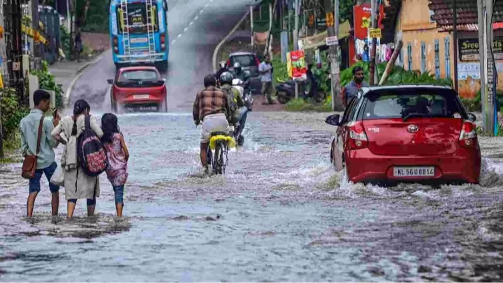 दक्षिण भारत में मानसून सक्रियता के दौरान पानी से भरी सड़क पर निकलते वाहन और लोग। दक्षिण भारत में मानसून सक्रियता के दौरान पानी से भरी सड़क पर निकलते वाहन और लोग।