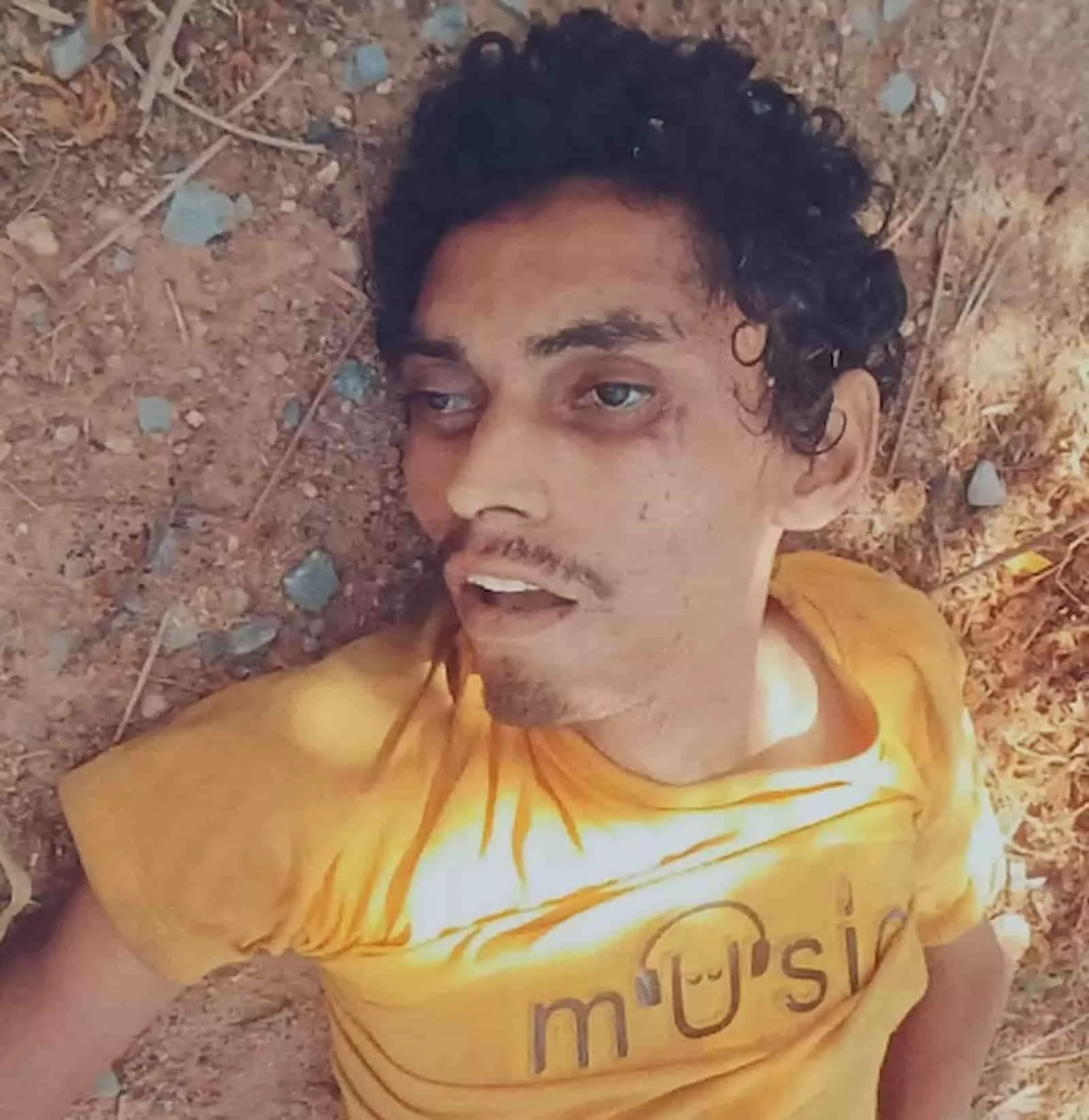 जमीन पर लेटे हुए पीले रंग की टी-शर्ट पहने एक अज्ञात युवक की तस्वीर। जमीन पर लेटे हुए पीले रंग की टी-शर्ट पहने एक अज्ञात युवक की तस्वीर।