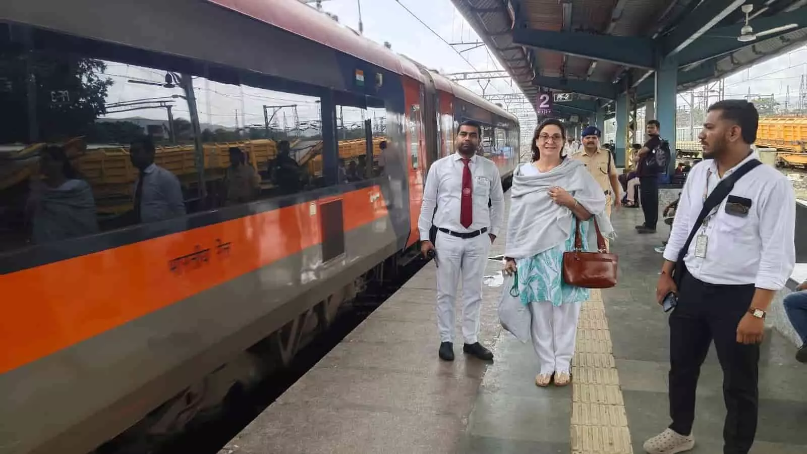 तस्वीर में कर्जत स्टेशन पर वंदे भारत एक्सप्रेस के पास खड़ी महिला यात्री और रेलवे कर्मचारी दिख रहे हैं। तस्वीर में कर्जत स्टेशन पर वंदे भारत एक्सप्रेस के पास खड़ी महिला यात्री और रेलवे कर्मचारी दिख रहे हैं।