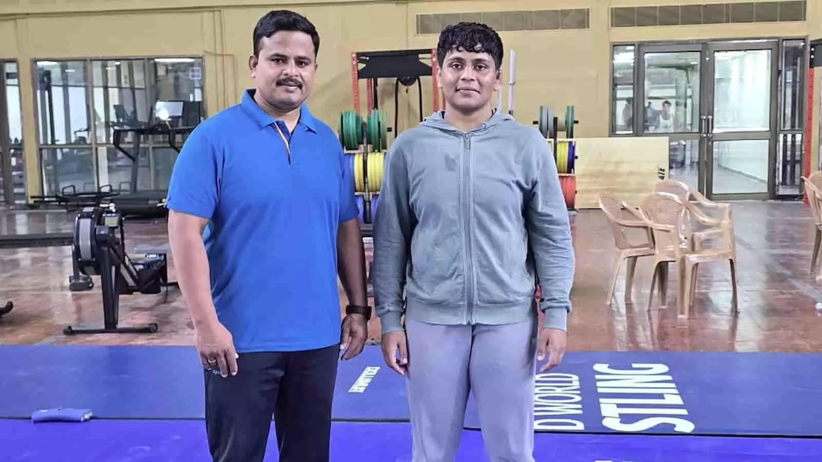 कुश्ती संकुल के मैट पर खड़े कोच दादासो लवटे और अमृता पुजारी। कुश्ती संकुल के मैट पर खड़े कोच दादासो लवटे और अमृता पुजारी।
