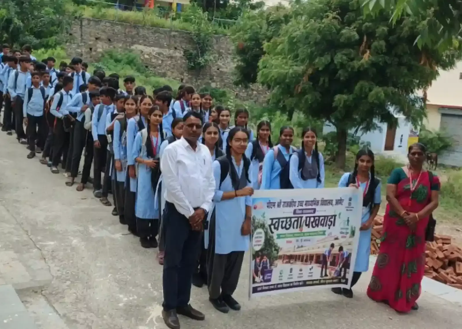 तस्वीर में दिख रही रैली में स्कूली छात्र और शिक्षक सड़क पर स्वच्छता बैनर के साथ मौजूद हैं। तस्वीर में दिख रही रैली में स्कूली छात्र और शिक्षक सड़क पर स्वच्छता बैनर के साथ मौजूद हैं।