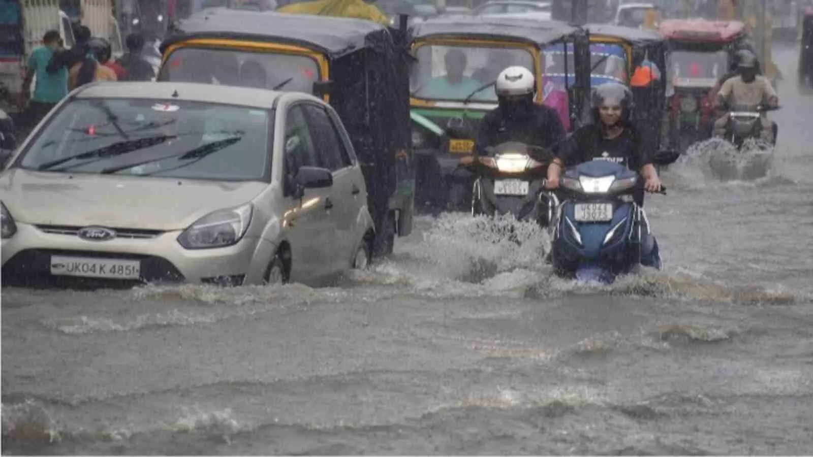 भारी बारिश के बीच उत्तर भारत की सड़क पर वाहन चलाते लोग और चलते राहगीर| भारी बारिश के बीच उत्तर भारत की सड़क पर वाहन चलाते लोग और चलते राहगीर|