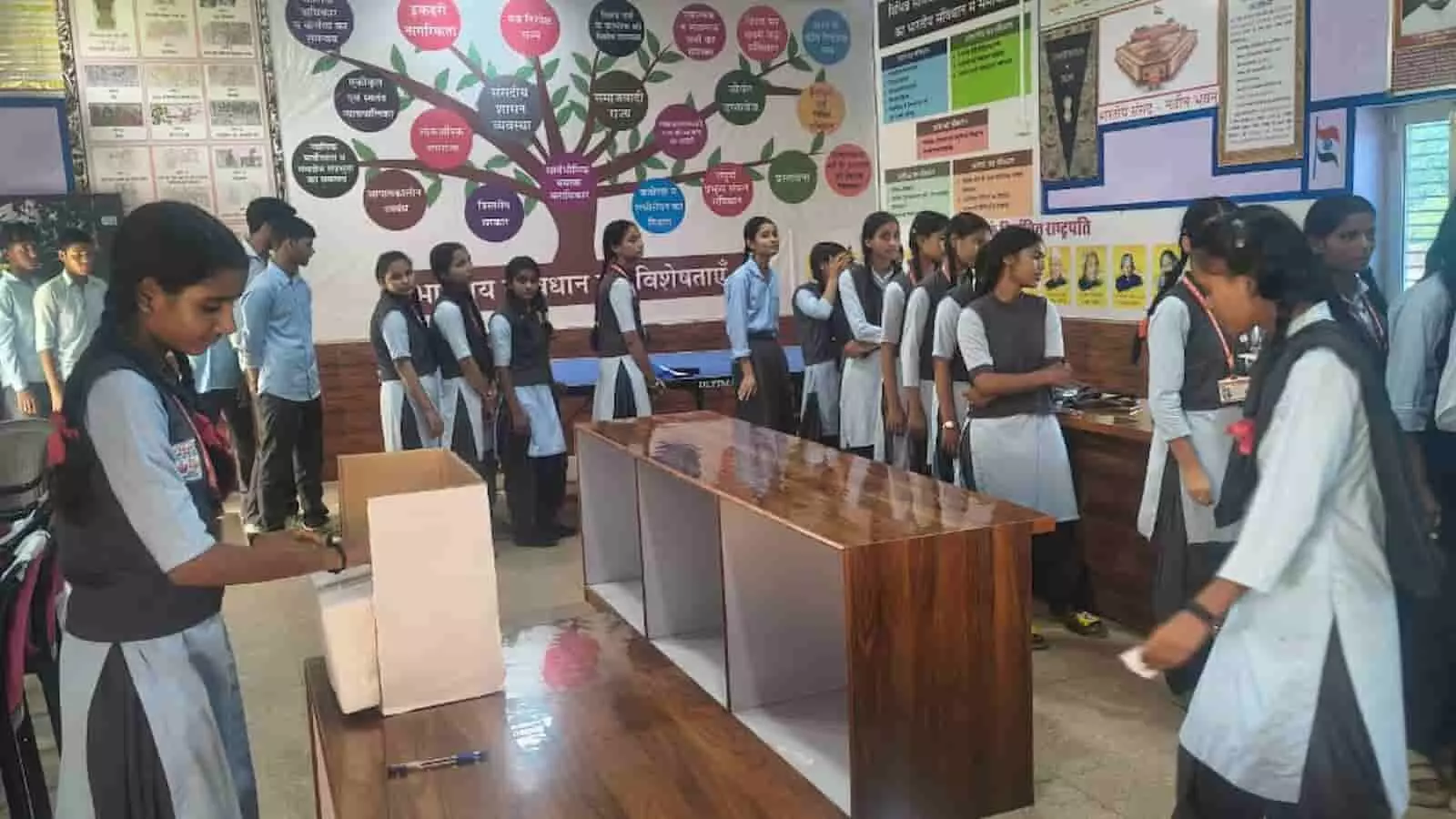 तस्वीर में छात्र-छात्राएं स्कूल के कमरे में मॉक पोलिंग बूथ पर मतदान का अभ्यास कर रहे हैं। तस्वीर में छात्र-छात्राएं स्कूल के कमरे में मॉक पोलिंग बूथ पर मतदान का अभ्यास कर रहे हैं।