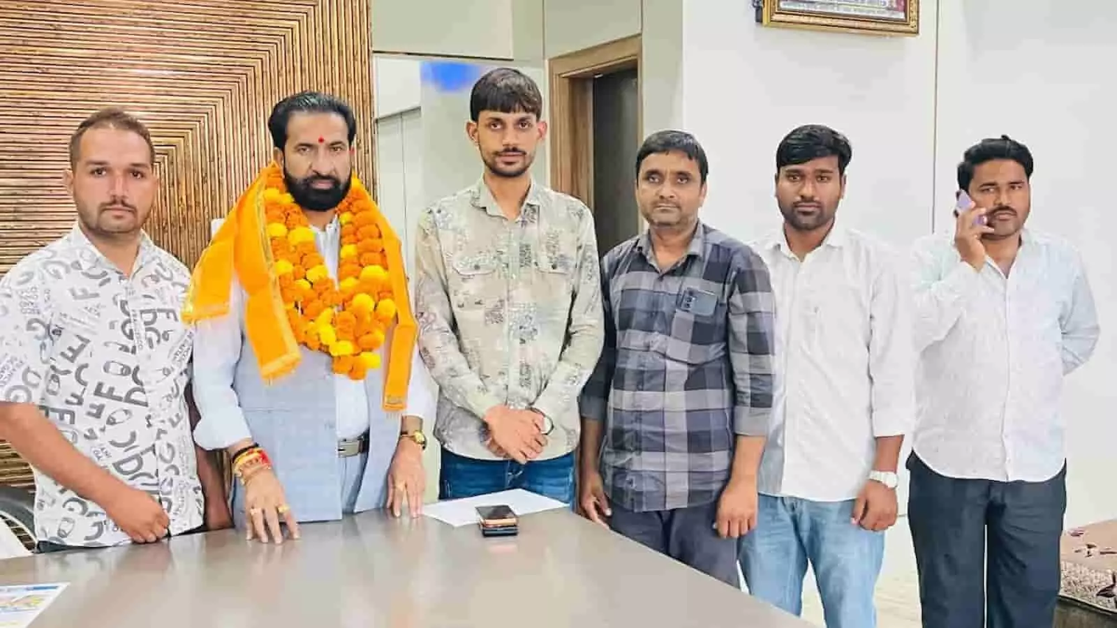 विधायक कार्यालय में विधायक अर्जुनलाल जीनगर और ग्रामीण एक साथ टेबल के पास खड़े होकर तस्वीर खिंचवाते हुए। विधायक कार्यालय में विधायक अर्जुनलाल जीनगर और ग्रामीण एक साथ टेबल के पास खड़े होकर तस्वीर खिंचवाते हुए।