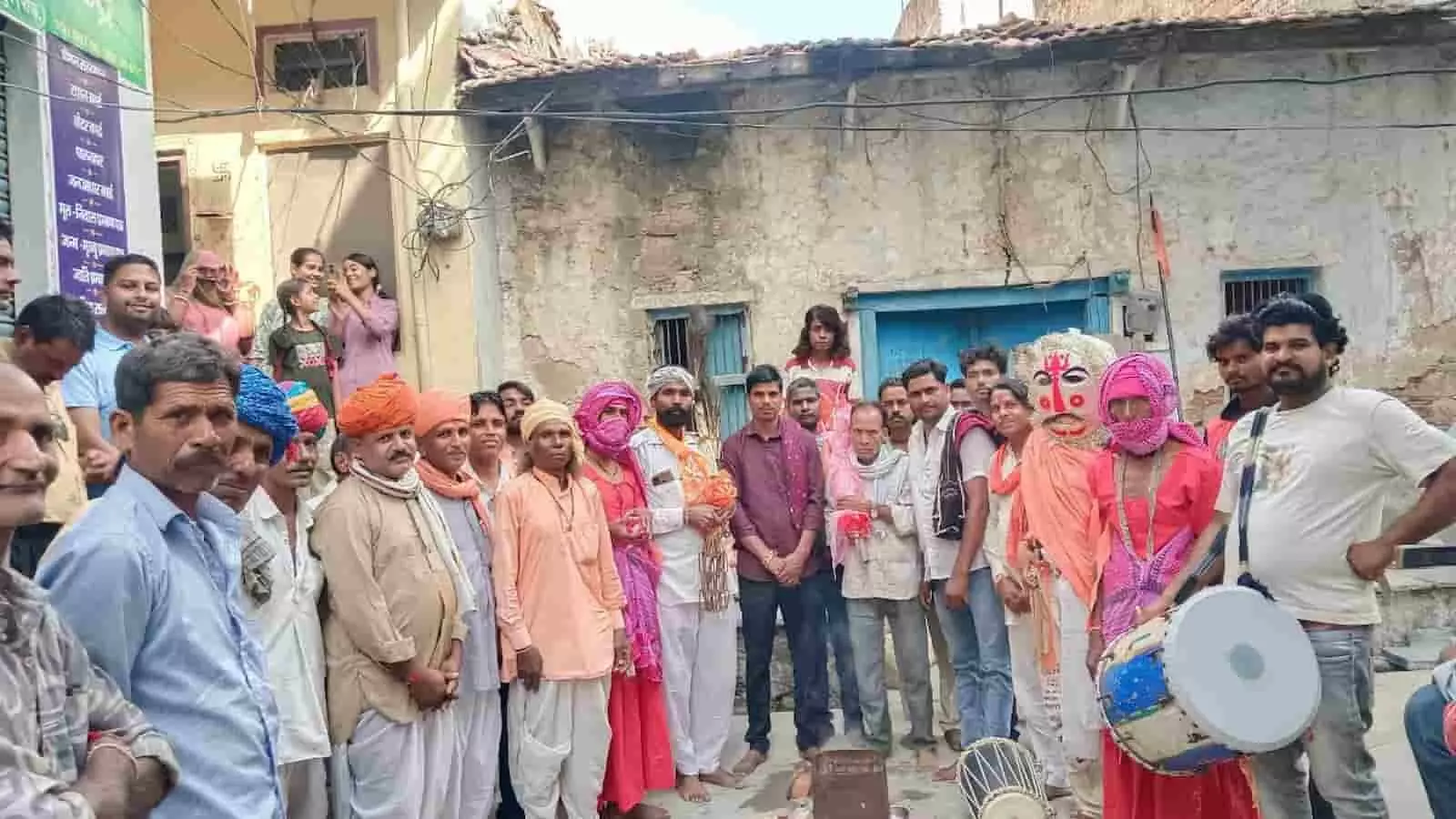 तस्वीर में ढोल-मांदल लिए गवरी कलाकार और स्थानीय ग्रामीण एक साथ खड़े होकर पारंपरिक रस्म निभाते दिख रहे हैं। तस्वीर में ढोल-मांदल लिए गवरी कलाकार और स्थानीय ग्रामीण एक साथ खड़े होकर पारंपरिक रस्म निभाते दिख रहे हैं।