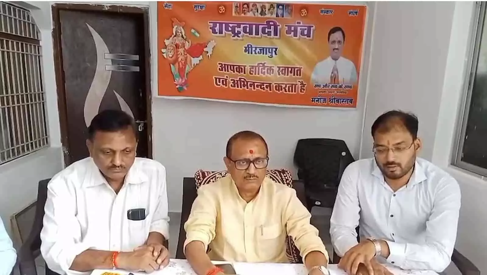 तस्वीर में राष्ट्रवादी मंच मिर्जापुर के बैनर के सामने तीन पुरुष कुर्सी पर बैठे हुए हैं। तस्वीर में राष्ट्रवादी मंच मिर्जापुर के बैनर के सामने तीन पुरुष कुर्सी पर बैठे हुए हैं।