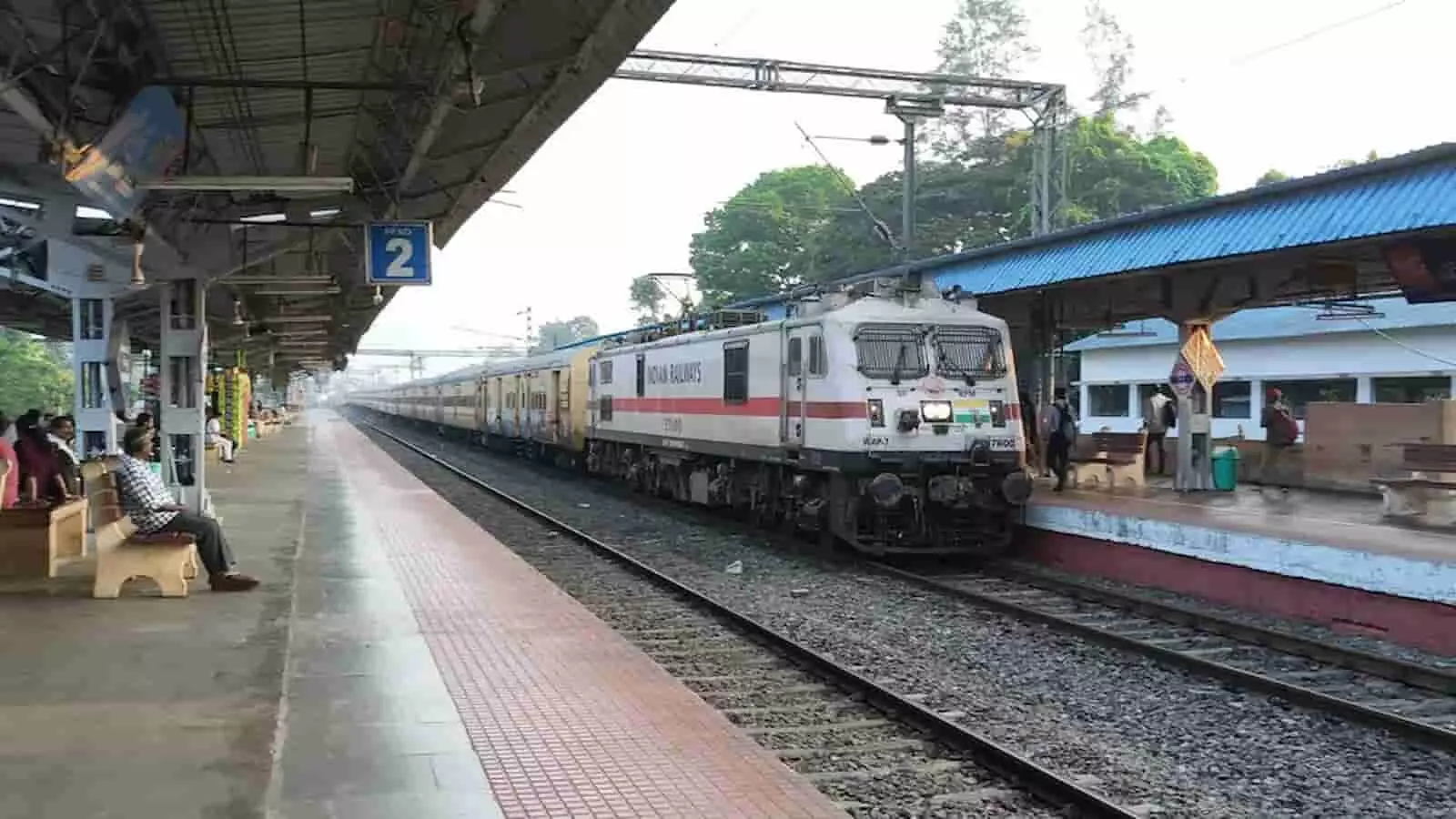 रेलवे स्टेशन के प्लेटफार्म पर खड़ी ट्रेन और पटरियों पर खड़ा इंजन दिख रहा है। रेलवे स्टेशन के प्लेटफार्म पर खड़ी ट्रेन और पटरियों पर खड़ा इंजन दिख रहा है।