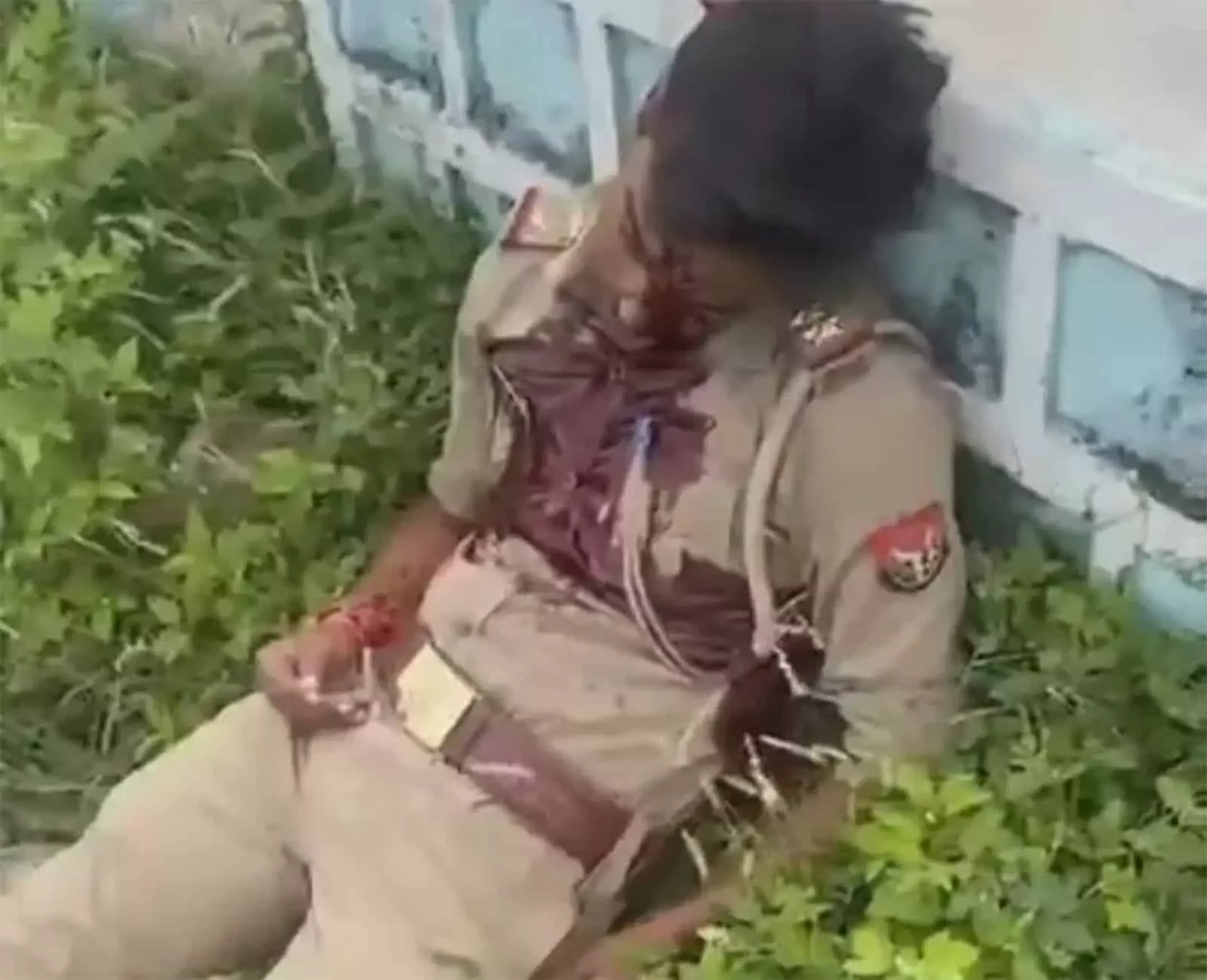 तस्वीर में उत्तर प्रदेश पुलिस की वर्दी पहने एक घायल पुलिसकर्मी दीवार के पास जमीन पर पड़ा है। तस्वीर में उत्तर प्रदेश पुलिस की वर्दी पहने एक घायल पुलिसकर्मी दीवार के पास जमीन पर पड़ा है।