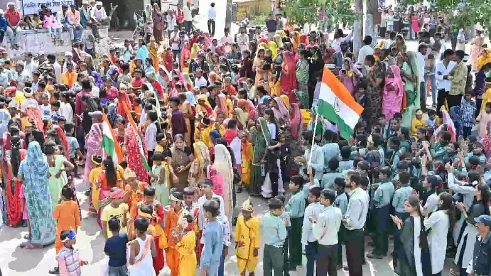 तस्वीर में दिख रही सड़क पर तिरंगा फहराते लोग और पोशाक पहने बच्चे शोभायात्रा में शामिल हैं। तस्वीर में दिख रही सड़क पर तिरंगा फहराते लोग और पोशाक पहने बच्चे शोभायात्रा में शामिल हैं।
