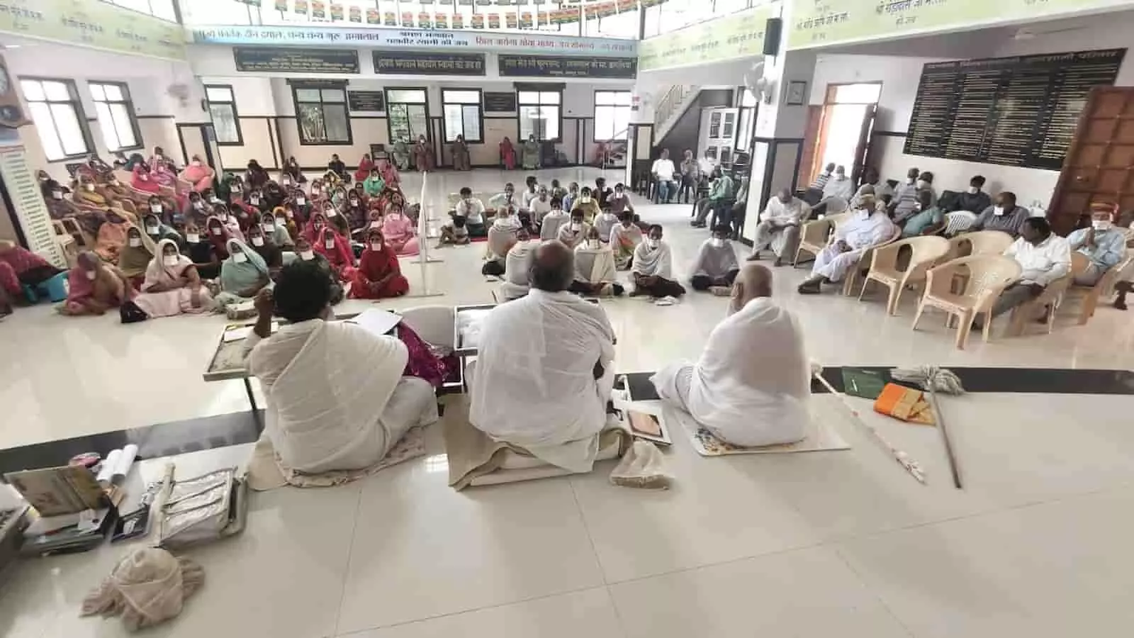 तस्वीर में सफेद वस्त्र धारण किए तीन जैन मुनि हॉल में उपस्थित श्रद्धालुओं की सभा को संबोधित कर रहे हैं। तस्वीर में सफेद वस्त्र धारण किए तीन जैन मुनि हॉल में उपस्थित श्रद्धालुओं की सभा को संबोधित कर रहे हैं।