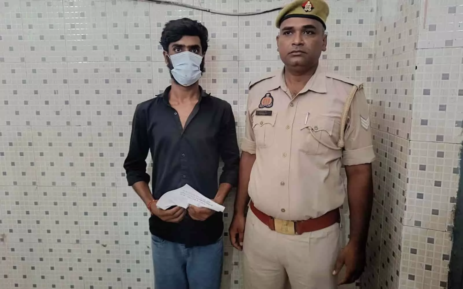तस्वीर में बाईं ओर मास्क पहना आरोपी और दाईं ओर खाकी वर्दी में पुलिसकर्मी खड़ा है। तस्वीर में बाईं ओर मास्क पहना आरोपी और दाईं ओर खाकी वर्दी में पुलिसकर्मी खड़ा है।