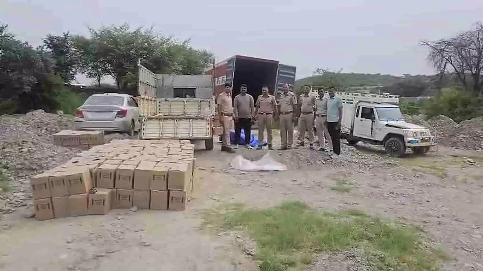 तस्वीर में खुली जगह पर पुलिसकर्मी जब्त कार्टन, पिकअप और कार के पास खड़े हैं। तस्वीर में खुली जगह पर पुलिसकर्मी जब्त कार्टन, पिकअप और कार के पास खड़े हैं।