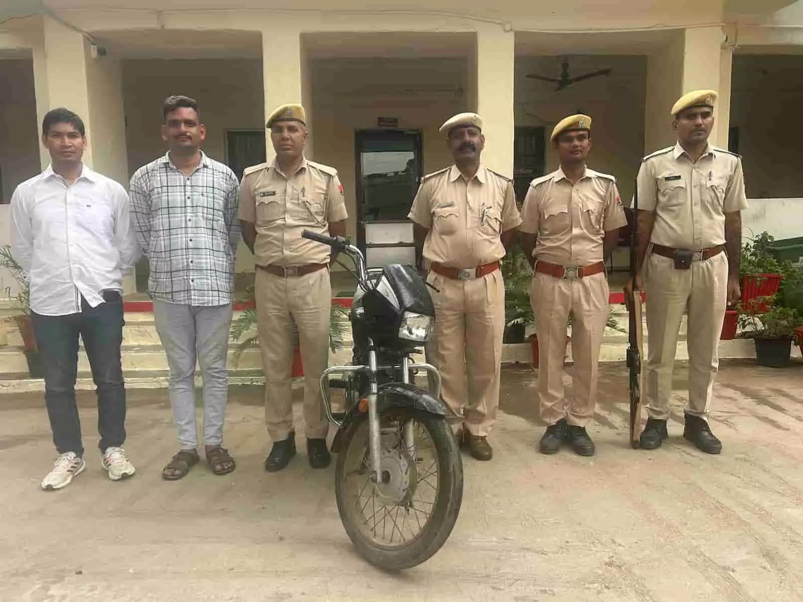 तस्वीर में बाएं से दाएं दो नागरिक कपड़ों में व्यक्ति और चार पुलिसकर्मी एक मोटरसाइकिल के साथ खड़े हैं। तस्वीर में बाएं से दाएं दो नागरिक कपड़ों में व्यक्ति और चार पुलिसकर्मी एक मोटरसाइकिल के साथ खड़े हैं।