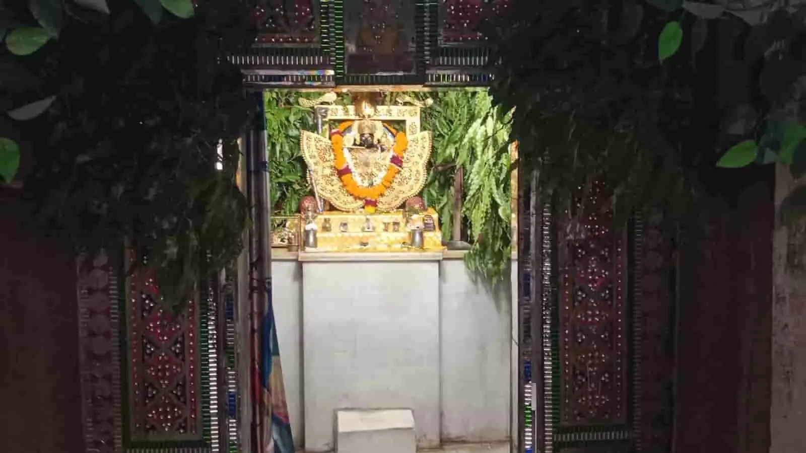 तस्वीर में फूलों और पत्तों से सजा हुआ मंदिर का गर्भगृह दिख रहा है। तस्वीर में फूलों और पत्तों से सजा हुआ मंदिर का गर्भगृह दिख रहा है।