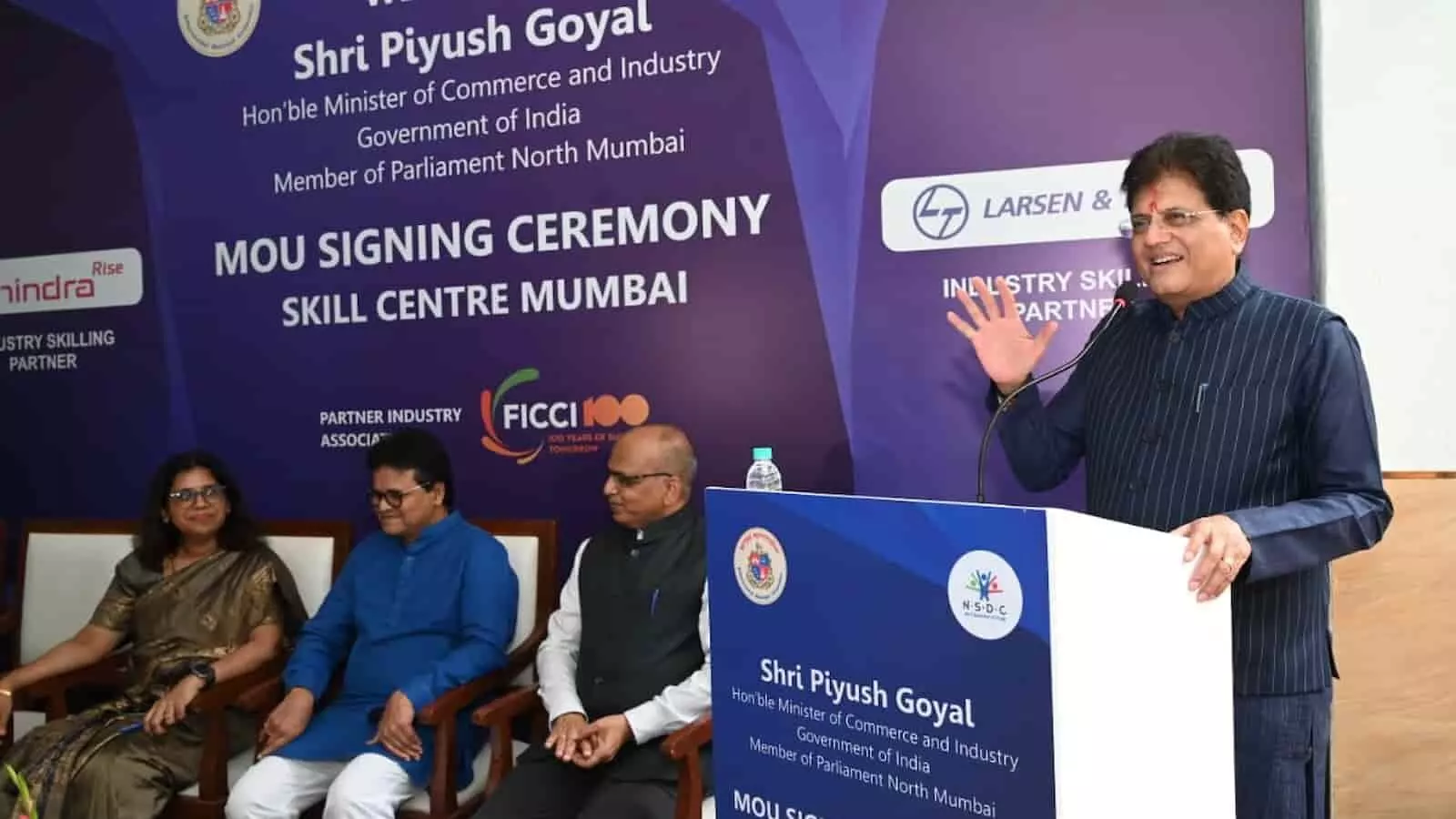 तस्वीर में मंच पर बैठे तीन लोगों के साथ पीयूष गोयल पोडियम पर भाषण दे रहे हैं। तस्वीर में मंच पर बैठे तीन लोगों के साथ पीयूष गोयल पोडियम पर भाषण दे रहे हैं।