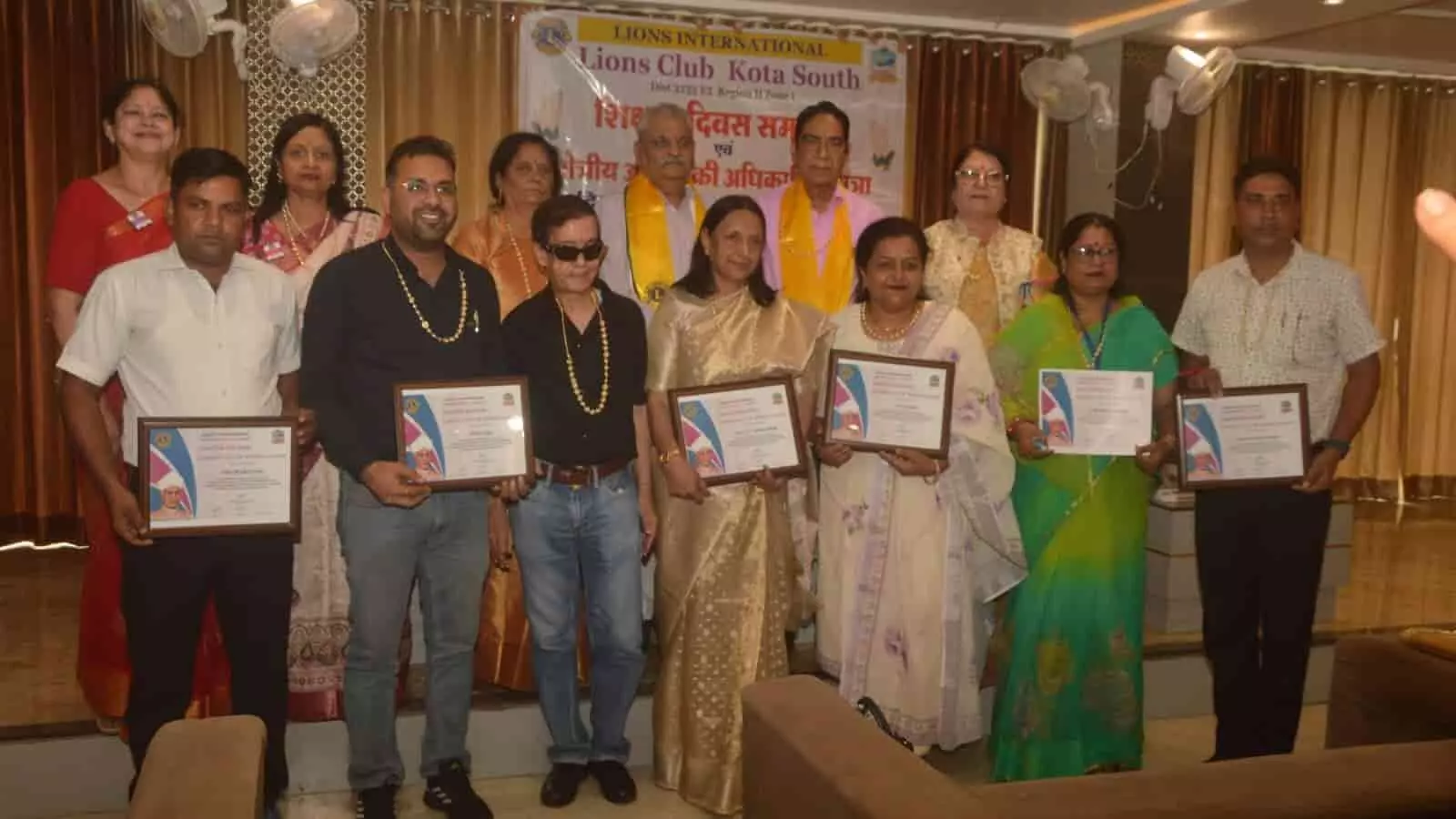 तस्वीर में लायंस क्लब के बैनर के सामने खड़े लोग सम्मान-पत्र दिखा रहे हैं। तस्वीर में लायंस क्लब के बैनर के सामने खड़े लोग सम्मान-पत्र दिखा रहे हैं।