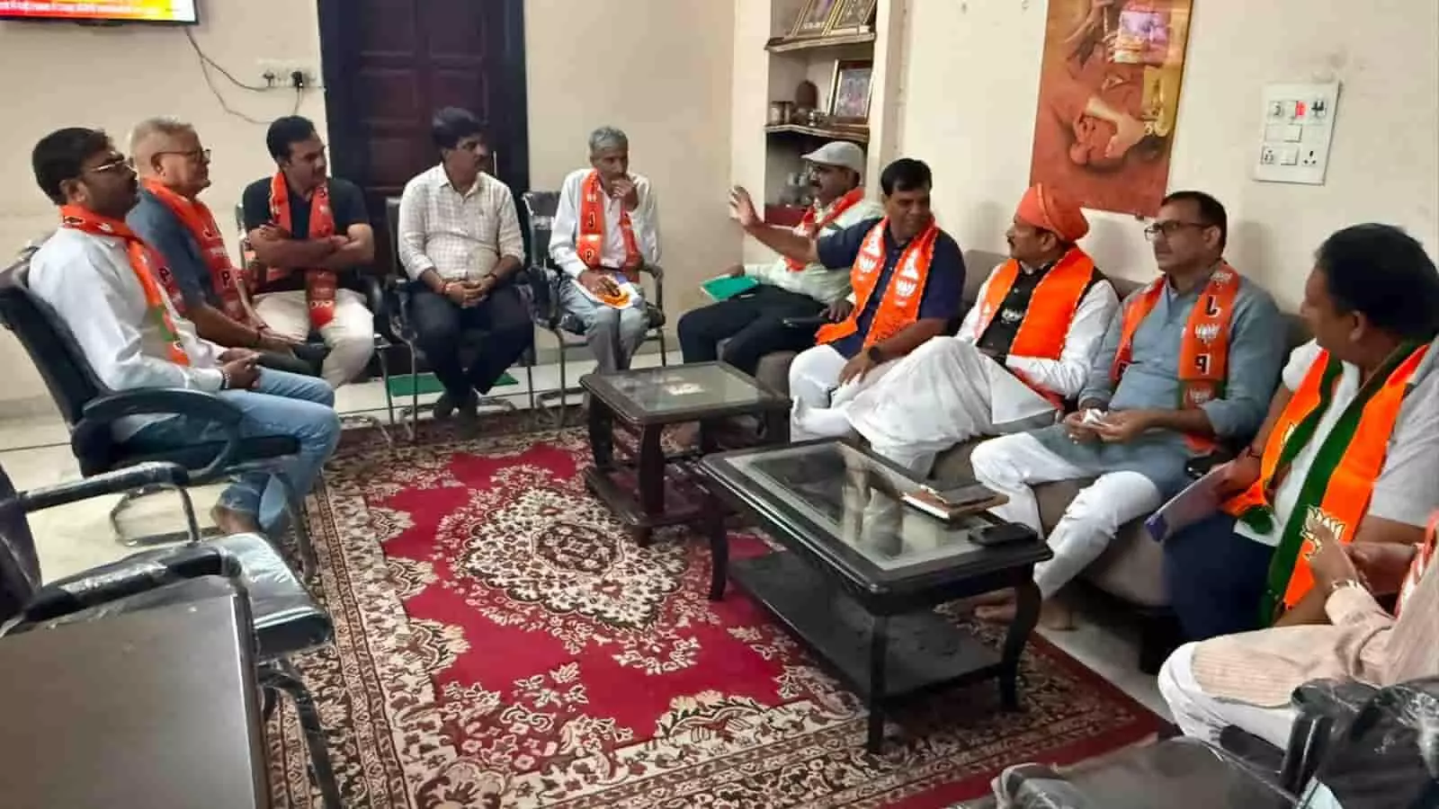 तस्वीर में बाएं कुर्सियों और दाएं सोफे पर भगवा दुपट्टा पहने पुरुष बैठक के लिए बैठे हैं। तस्वीर में बाएं कुर्सियों और दाएं सोफे पर भगवा दुपट्टा पहने पुरुष बैठक के लिए बैठे हैं।