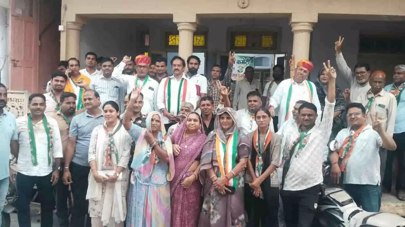 तस्वीर में तिरंगा दुपट्टा पहने लोग जीत का संकेत देते हुए इमारत बाहर खड़े हैं। तस्वीर में तिरंगा दुपट्टा पहने लोग जीत का संकेत देते हुए इमारत बाहर खड़े हैं।