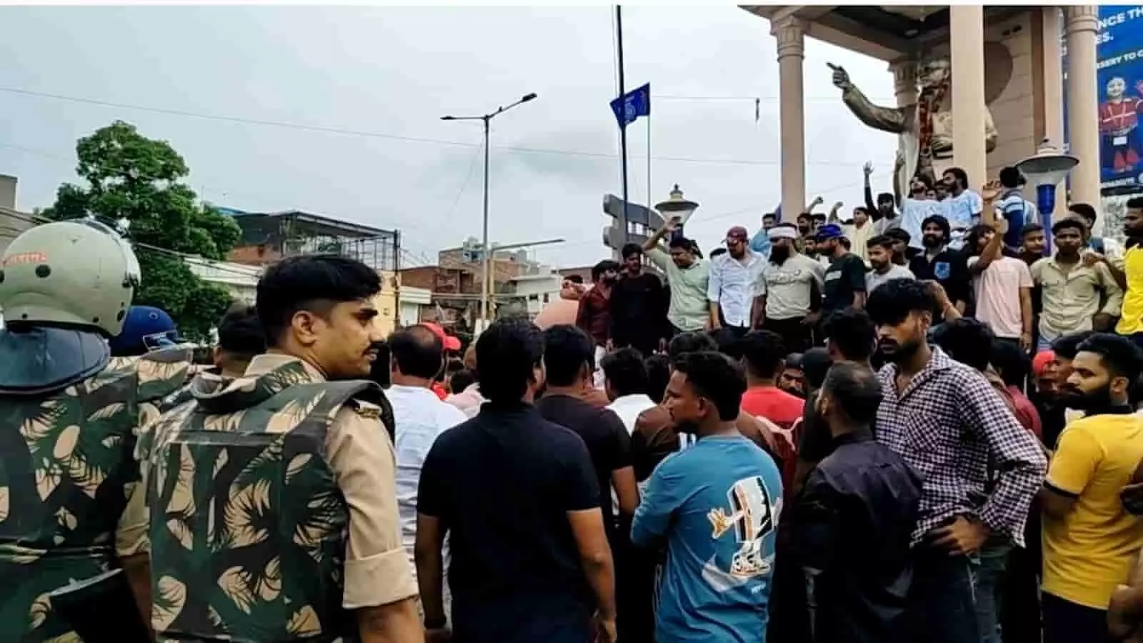 तस्वीर में बाईं ओर पुलिसकर्मी और दाईं ओर मूर्ति के पास भीड़ इकट्ठा होकर प्रदर्शन कर रही है। तस्वीर में बाईं ओर पुलिसकर्मी और दाईं ओर मूर्ति के पास भीड़ इकट्ठा होकर प्रदर्शन कर रही है।