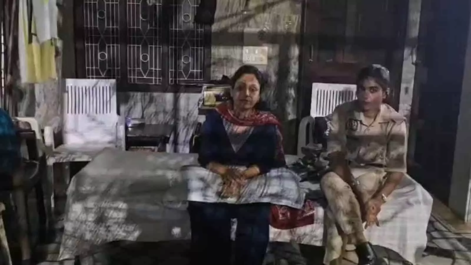 तस्वीर में बाएं बैठी महिला और दाएं बैठी महिला पुलिसकर्मी घर के बाहर नजर आ रही हैं। तस्वीर में बाएं बैठी महिला और दाएं बैठी महिला पुलिसकर्मी घर के बाहर नजर आ रही हैं।