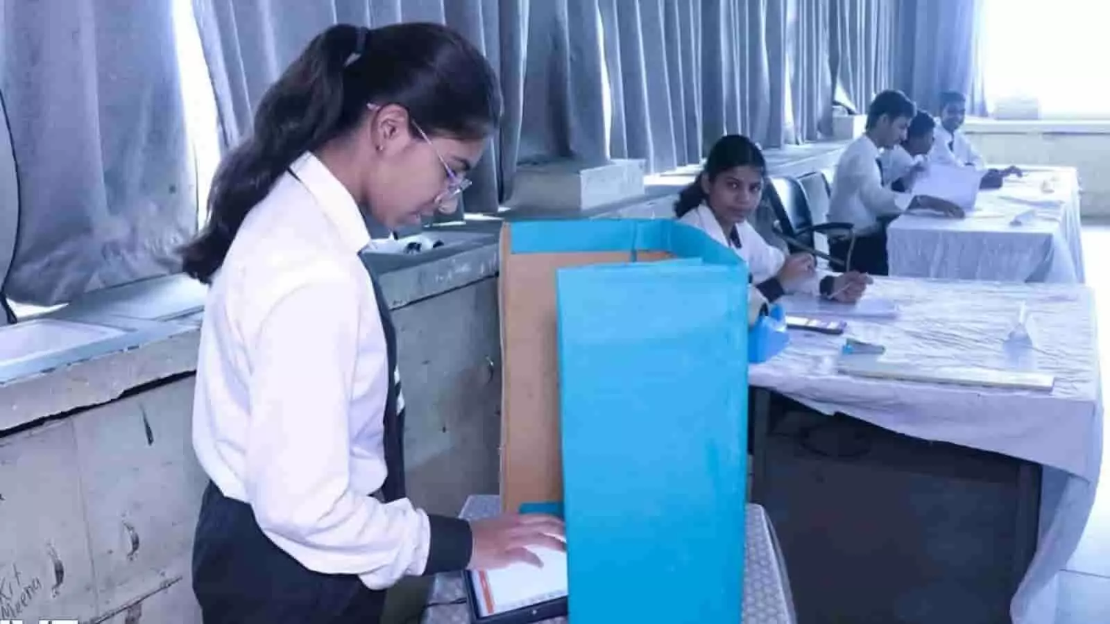 तस्वीर में एक छात्रा नीले बूथ पर मतदान प्रक्रिया का अभ्यास कर रही है। तस्वीर में एक छात्रा नीले बूथ पर मतदान प्रक्रिया का अभ्यास कर रही है।