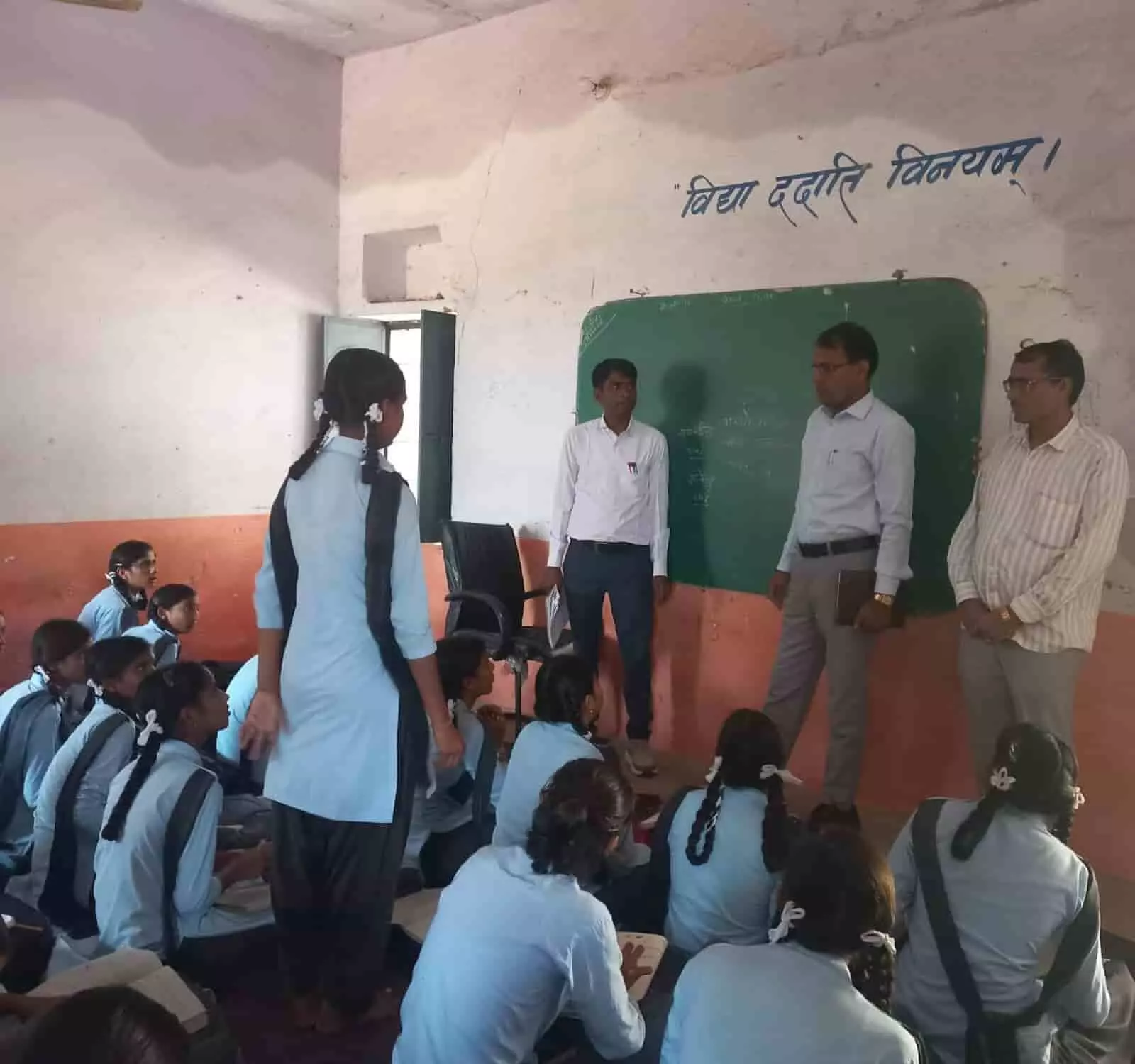 तस्वीर में बाएं से दाएं खड़े तीन अधिकारी कक्षा के ब्लैकबोर्ड के सामने छात्राओं से बात कर रहे हैं। तस्वीर में बाएं से दाएं खड़े तीन अधिकारी कक्षा के ब्लैकबोर्ड के सामने छात्राओं से बात कर रहे हैं।