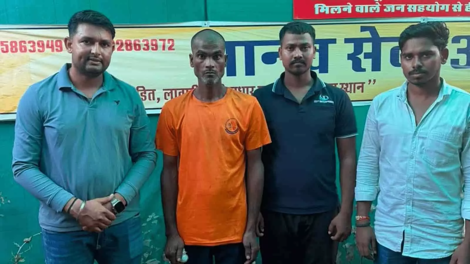 तस्वीर में बाईं ओर से चार पुरुष आश्रम के बैनर के सामने एक कतार में खड़े हैं। तस्वीर में बाईं ओर से चार पुरुष आश्रम के बैनर के सामने एक कतार में खड़े हैं।