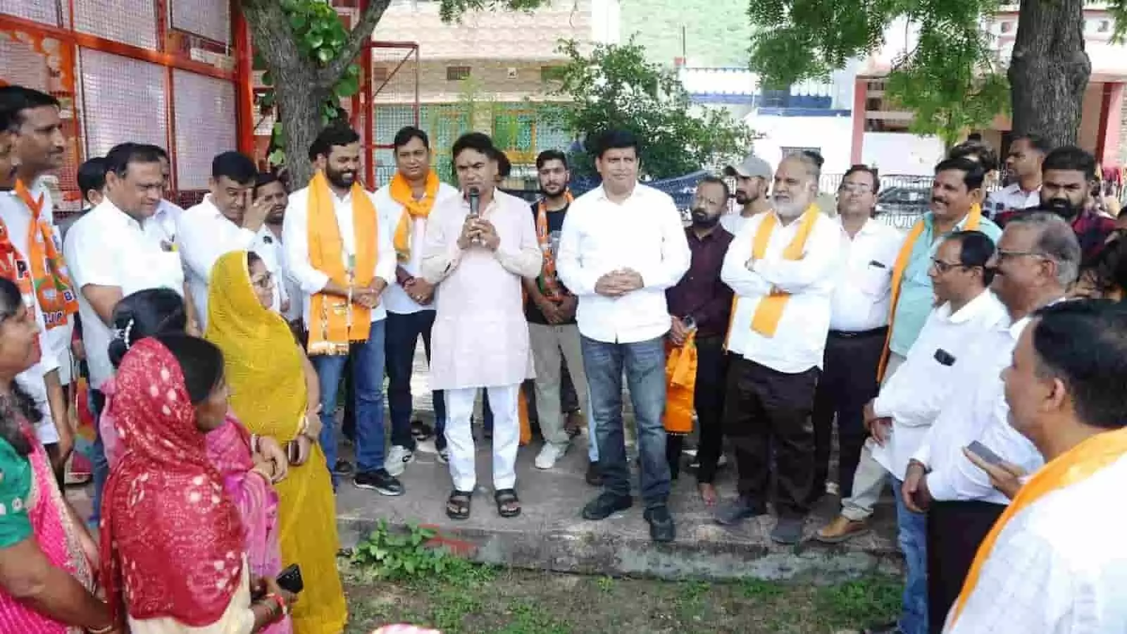 तस्वीर में दिख रहे पुरुष और महिलाएं खुले स्थान पर खड़े होकर एक वक्ता की बात सुन रहे हैं। तस्वीर में दिख रहे पुरुष और महिलाएं खुले स्थान पर खड़े होकर एक वक्ता की बात सुन रहे हैं।