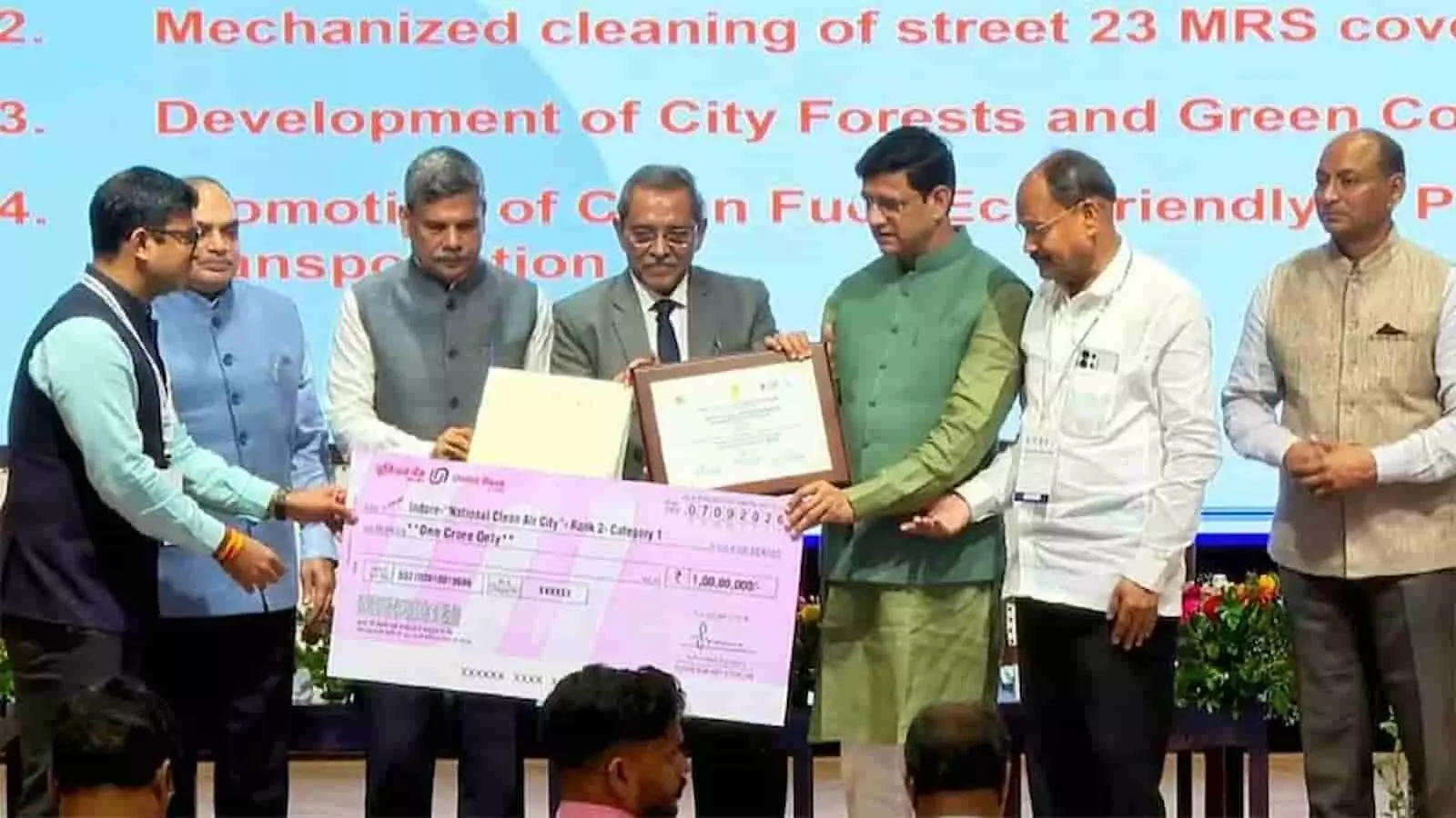 मंच पर अधिकारी स्वच्छ वायु सर्वेक्षण का पुरस्कार और चेक प्रदान कर रहे हैं। मंच पर अधिकारी स्वच्छ वायु सर्वेक्षण का पुरस्कार और चेक प्रदान कर रहे हैं।