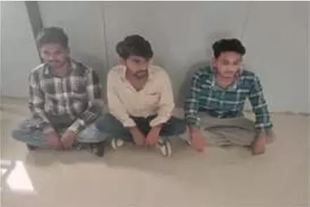 तस्वीर में बाईं से दाईं ओर साइबर ठगी के आरोप में पकड़े गए तीन युवक पुलिस हिरासत में जमीन पर बैठे हैं। तस्वीर में बाईं से दाईं ओर साइबर ठगी के आरोप में पकड़े गए तीन युवक पुलिस हिरासत में जमीन पर बैठे हैं।