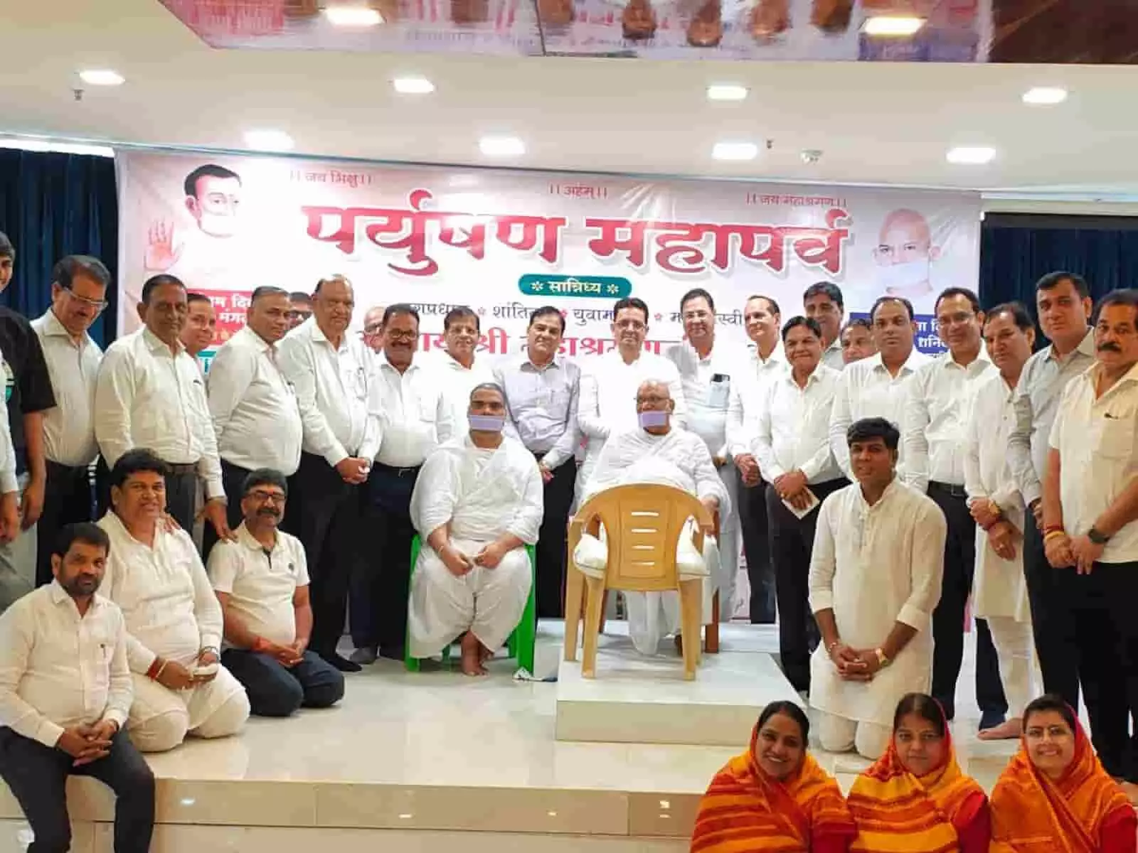 तस्वीर में दिख रही सभा में बैनर के आगे दो जैन मुनि और अन्य श्रद्धालु मंच पर साथ खड़े हैं। तस्वीर में दिख रही सभा में बैनर के आगे दो जैन मुनि और अन्य श्रद्धालु मंच पर साथ खड़े हैं।