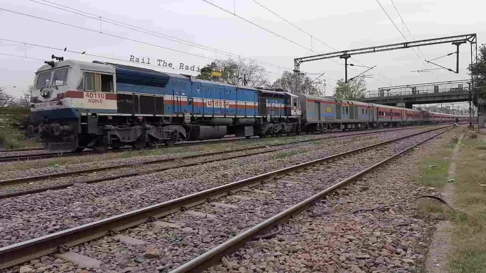 तस्वीर में रेलवे ट्रैक पर खड़ी एक ट्रेन और उसका इंजन दिखाई दे रहा है। तस्वीर में रेलवे ट्रैक पर खड़ी एक ट्रेन और उसका इंजन दिखाई दे रहा है।