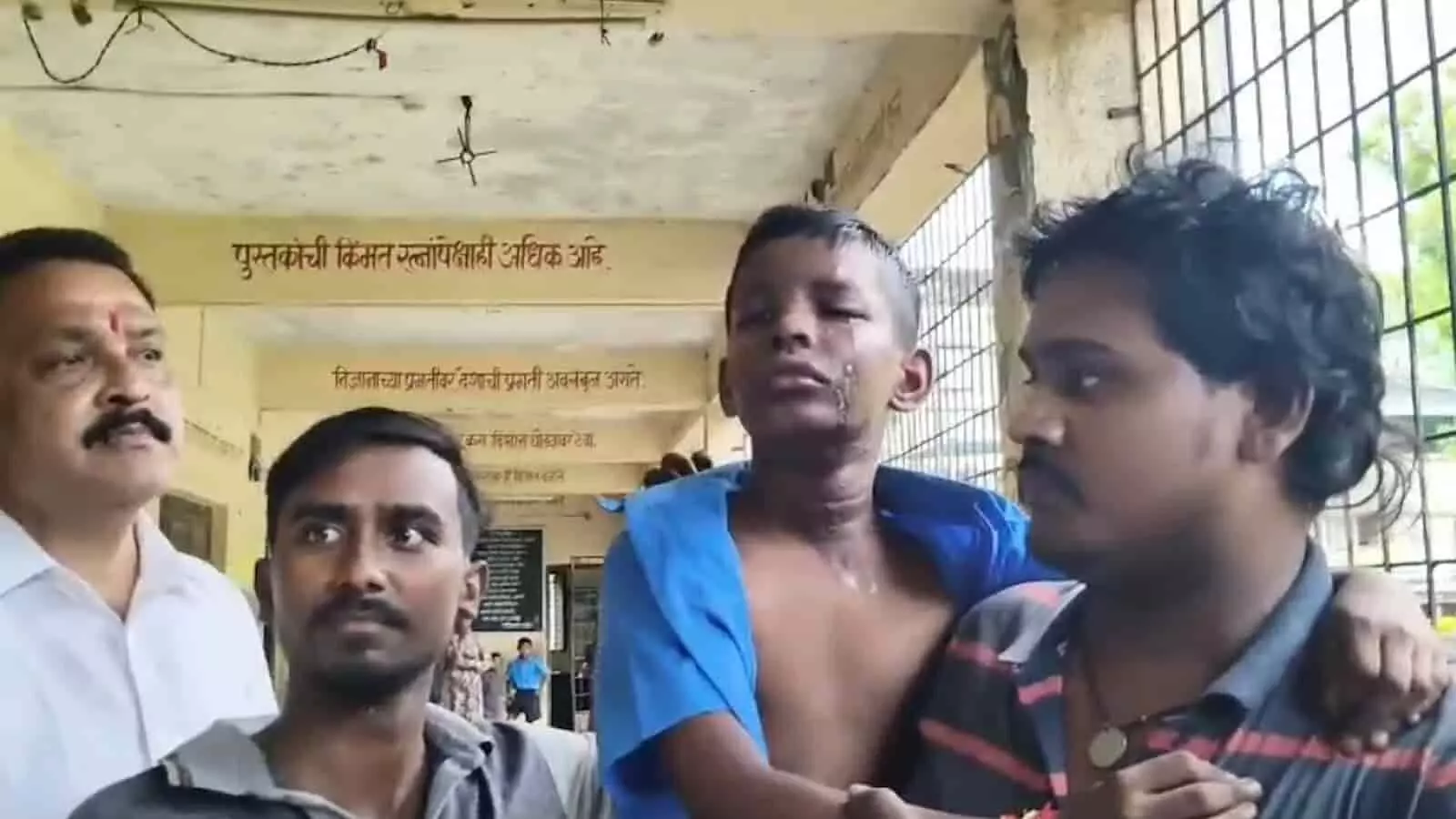 तस्वीर में बाएं से दाएं खड़े पुरुष स्कूल के बरामदे में घायल छात्र को थामे हुए हैं। तस्वीर में बाएं से दाएं खड़े पुरुष स्कूल के बरामदे में घायल छात्र को थामे हुए हैं।