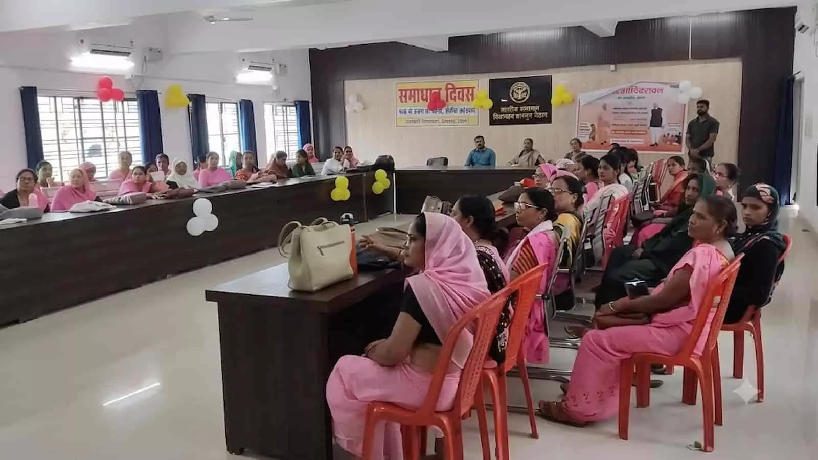 तस्वीर में गुलाबी साड़ी पहनी महिलाएं तहसील सभागार में आयोजित एक कार्यक्रम के दौरान बैठी हैं। तस्वीर में गुलाबी साड़ी पहनी महिलाएं तहसील सभागार में आयोजित एक कार्यक्रम के दौरान बैठी हैं।