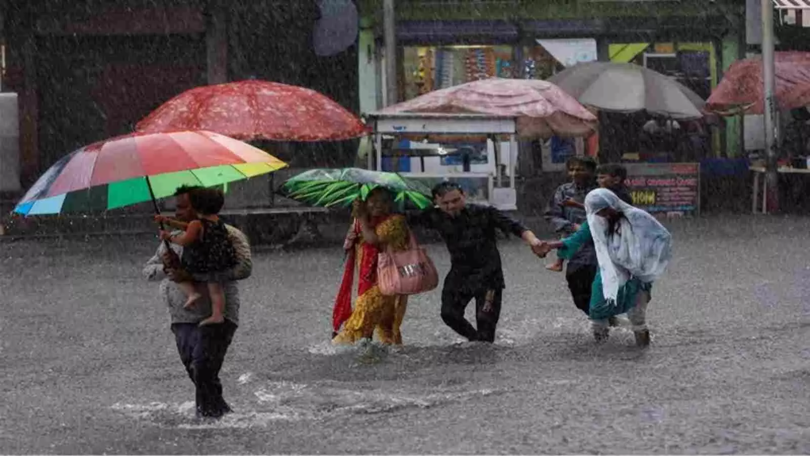 दक्षिण भारत में भारी बारिश के दौरान छतरियां लेकर जलभराव से गुजरते हुए लोग। दक्षिण भारत में भारी बारिश के दौरान छतरियां लेकर जलभराव से गुजरते हुए लोग।