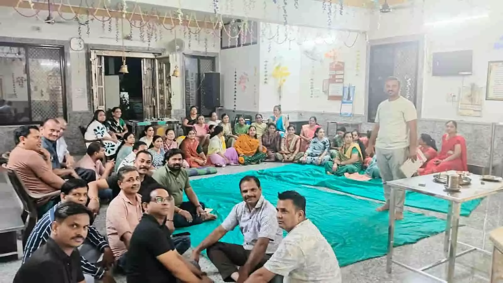 तस्वीर में पुरुष और महिलाएं खेरवाड़ा के जैन मंदिर परिसर में जमीन पर बैठकर बैठक कर रहे हैं। तस्वीर में पुरुष और महिलाएं खेरवाड़ा के जैन मंदिर परिसर में जमीन पर बैठकर बैठक कर रहे हैं।