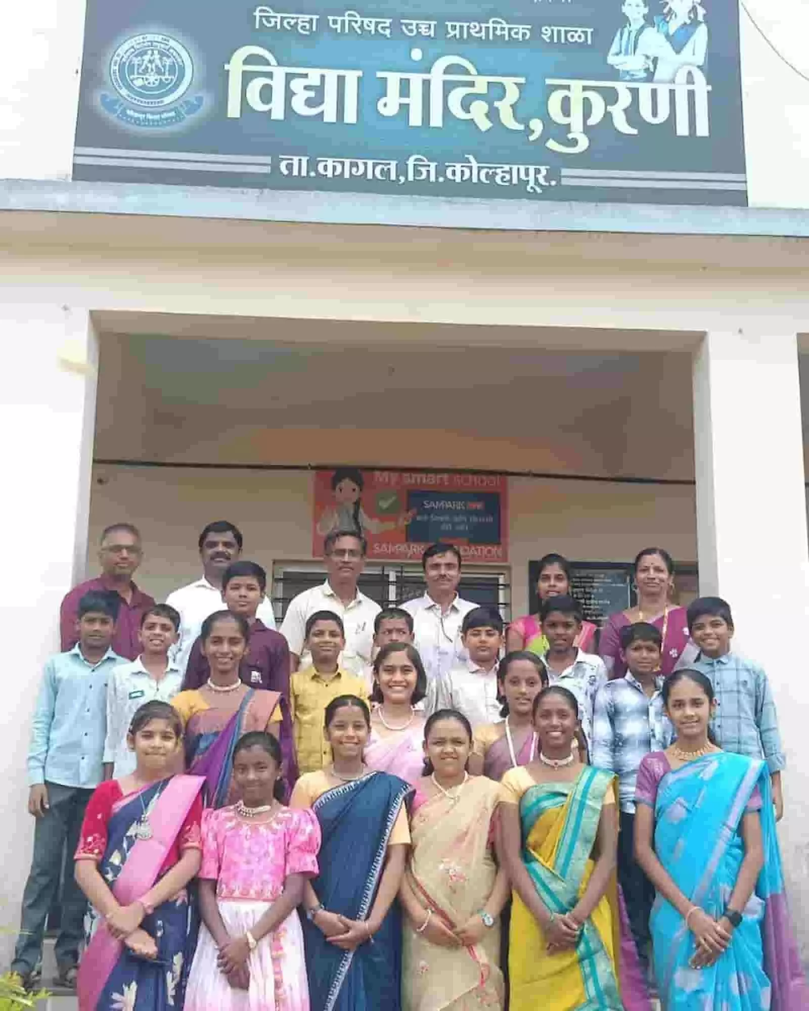 तस्वीर में विद्या मंदिर कुरणी इमारत के सामने खड़े शिक्षक और छात्र पोज देते हुए दिख रहे हैं। तस्वीर में विद्या मंदिर कुरणी इमारत के सामने खड़े शिक्षक और छात्र पोज देते हुए दिख रहे हैं।