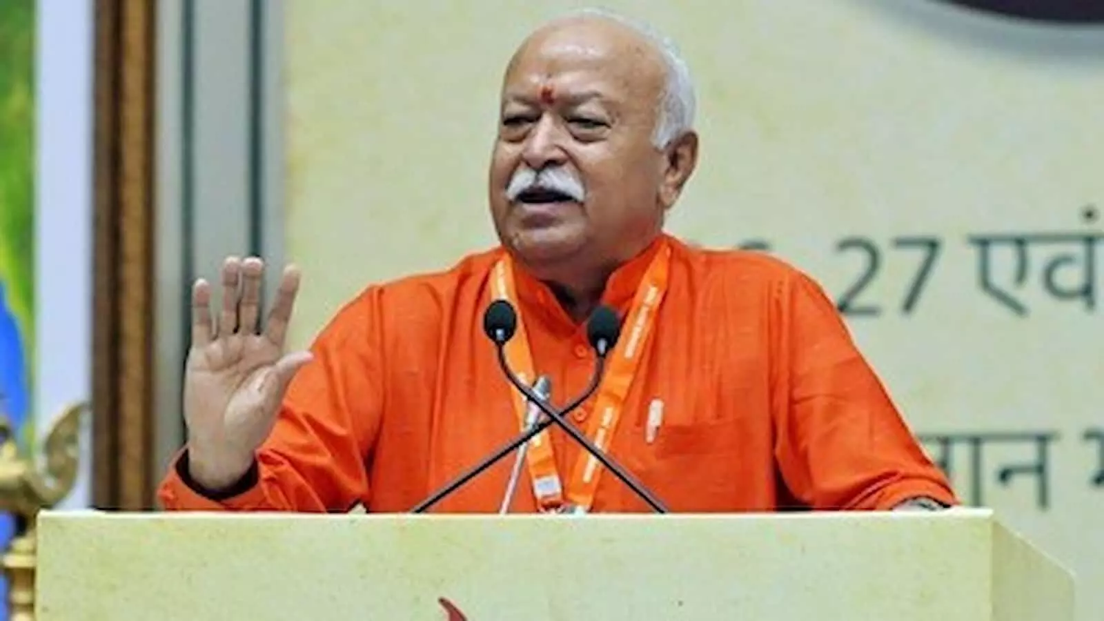तस्वीर में दिख रहे मोहन भागवत भगवा कुर्ता पहने मंच पर माइक के सामने हाथ उठाकर बोल रहे हैं। तस्वीर में दिख रहे मोहन भागवत भगवा कुर्ता पहने मंच पर माइक के सामने हाथ उठाकर बोल रहे हैं।