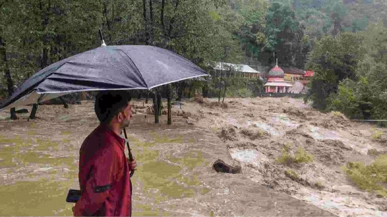 पहाड़ी क्षेत्र में बहते उफनते पानी के पास छाता लिए व्यक्ति दिखाई दे रहा है। पहाड़ी क्षेत्र में बहते उफनते पानी के पास छाता लिए व्यक्ति दिखाई दे रहा है।
