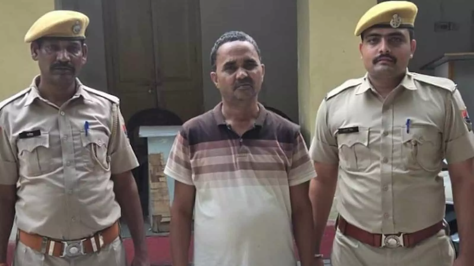 तस्वीर में पुलिसकर्मियों के बीच खड़े एक व्यक्ति को थाने में देखा जा सकता है। तस्वीर में पुलिसकर्मियों के बीच खड़े एक व्यक्ति को थाने में देखा जा सकता है।