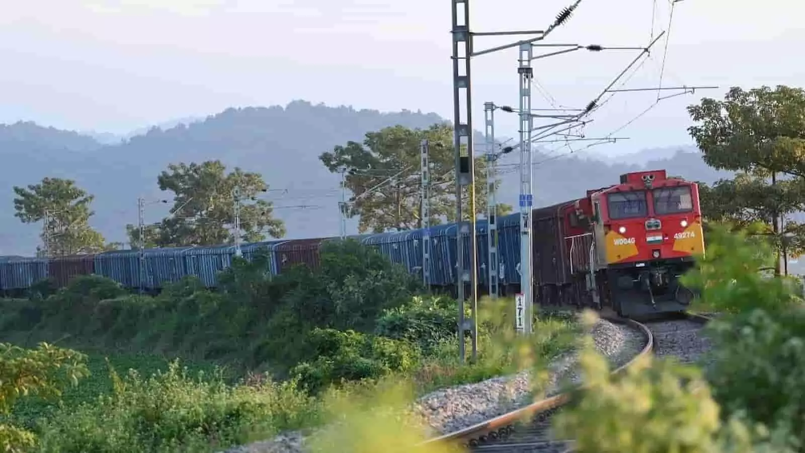 तस्वीर में हरी-भरी पहाड़ियों के बीच रेलवे ट्रैक पर मालगाड़ी दौड़ती हुई नजर आ रही है। तस्वीर में हरी-भरी पहाड़ियों के बीच रेलवे ट्रैक पर मालगाड़ी दौड़ती हुई नजर आ रही है।