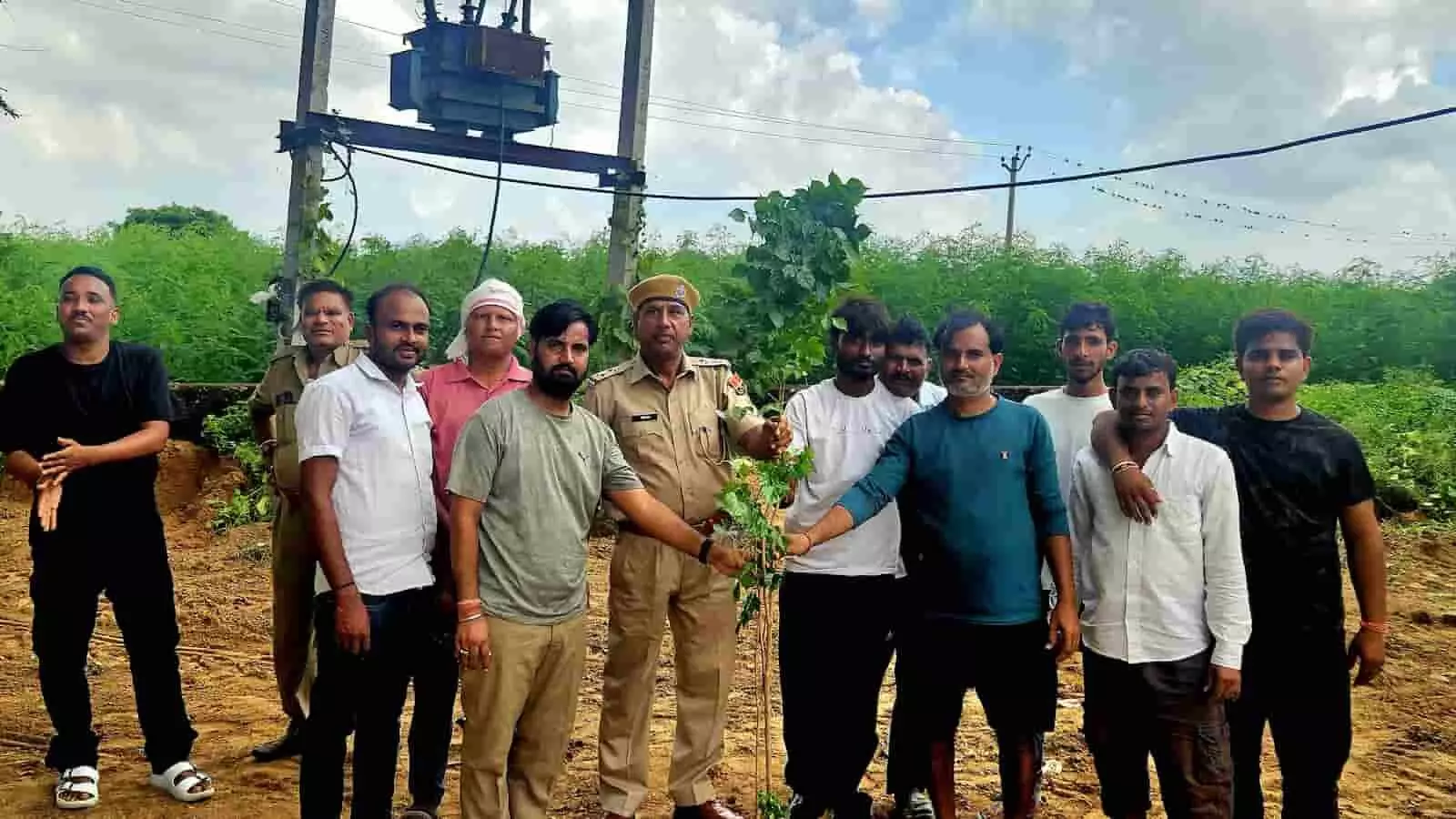 तस्वीर में बाएं से दाएं खड़े पुलिस अधिकारी और ग्रामीण हाथ मिलाकर एक पौधे को रोपते दिख रहे हैं। तस्वीर में बाएं से दाएं खड़े पुलिस अधिकारी और ग्रामीण हाथ मिलाकर एक पौधे को रोपते दिख रहे हैं।
